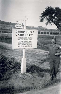 US soldier in front of sign indicating mass grave. (photo credits: US Signal Corps Foto, Courtesy of USHMM)